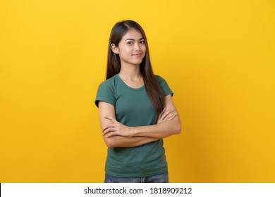 Beauty Asian Confidence Teenager In Green Tee Shirt Folded Arms And Smiling Stand Isolated On Yellow Background In Studio.