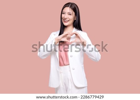 Beauty Asian woman making heart shape hand sign isolated on pink background.