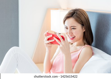 Beauty Asian Woman Play Mobile Game By Smartphone Happily On The Bed At Home