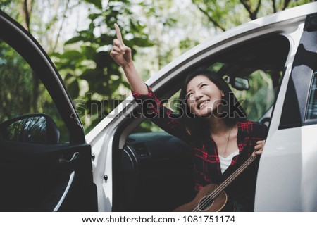 Beauty Asian woman pointing and having fun at outdoors summer with Ukulele in white car. Traveling of photographer concept. Hipster style and Solo woman theme. Lifestyle and Happiness life theme.