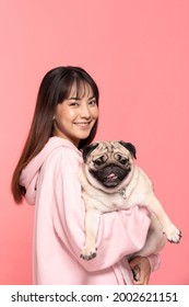 Beauty Asian Young Woman Holding Dog Pug Breed On Her Arm Smile And Happiness,Owner Hug Her Cute Pet Dog With Love On Pink Background,Young Girl With Adorable Dog Purebred Pug Breed Looking On Camera 