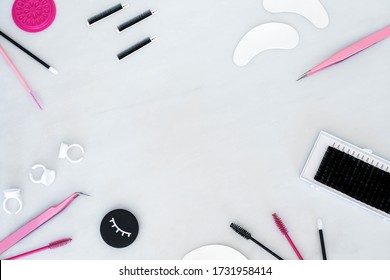 A beauty background styled with lash extension treatment products, tools and equipment.  Flat lay frame on a white background with space in the centre for text copy