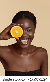 
Beauty. Black Woman With Healthy Face Skin Squeezing Orange In Hand. Beautiful Smiling Girl Model With Natural Makeup, Glowing Facial Skin And Citrus Fruit. Vitamin C Cosmetics Concept