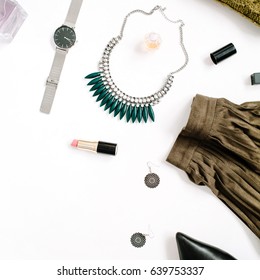 Beauty blog concept. Female clothes and accessories: green skirt and sweater, watches, necklace, lipstick, shoes, sunglasses on white background. Flat lay, top view trendy fashion feminine background.