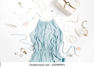 Beauty blog concept. Woman clothes and accessories: blue dress, purse, watches, bracelet, necklace, rings, lipstick on white background. Flat lay, top view trendy fashion feminine background.