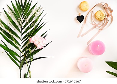 Beauty blogger flat lay on white.  Green leaves and carnation flower, pink ombre candles, heart, macaroons. Woman decorating ideas. Negative space for text