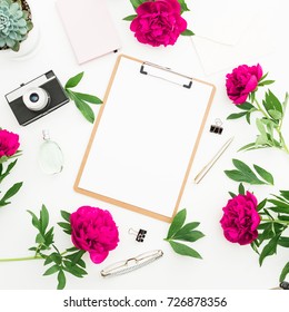 Beauty Blogger Or Freelancer Desk With Clipboard, Notebook, Retro Camera, Red Peonies And Accessories On White Background. Flat Lay, Top View.