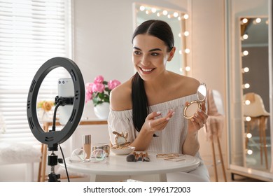 Beauty blogger with makeup product recording video in dressing room at home. Using ring lamp and smartphone - Powered by Shutterstock