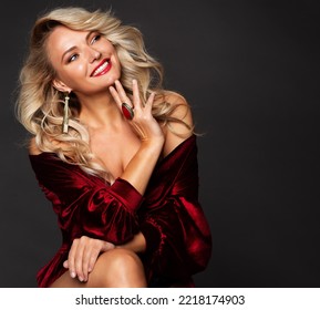 Beauty Blond Woman with Red Lips cheerful Smile. Luxury Fashion Girl with Blonde Curly Hair. Elegant Lady with Golden Earring and Ring Jewelry. Happy Model smiling over Black Studio background