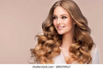 Beauty blonde girl with long  and   shiny wavy  hair .  Beautiful   woman model with curly hairstyle . Fashion, cosmetics and makeup