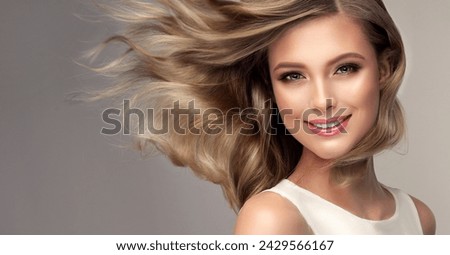Beauty blonde girl with long  and   shiny wavy  hair .  Beautiful   woman model with curly hairstyle . Perm, trichology and care