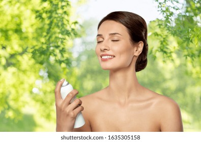 Beauty, Bodycare And People Concept - Beautiful Young Woman Applying Facial Spray Or Mist To Her Face Skin Over Green Natural Background