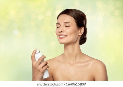 Beauty, Bodycare And People Concept - Beautiful Young Woman Applying Facial Spray Or Mist To Her Face Skin Over Lights On Green Background