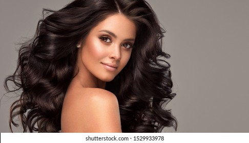 Belle brune avec une longue et   cheveux noirs ondulés et brillants.  Beau   modèle de femme avec coiffure bouclée.