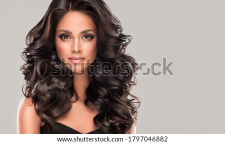 Beauty brunette girl with long  and   shiny wavy black hair .  Beautiful   woman model with curly hairstyle .