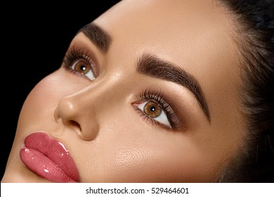 Beauty Brunette Woman With Perfect Makeup. Beautiful Professional Make-up. Person Perfect Eyebrows. Skin Care, Foundation, Contouring. Beauty Girl's Face Isolated On Black Background