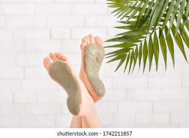Beauty care in spa. Foot care with clay on white brick wall, with palm leaves, close up, free space