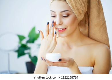 Beauty and Care. Woman with Pure Skin and Towel on the Head Pour Cream on Face. Body Care. Skin Care. High Resolution