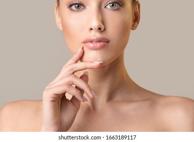 Beauty Concept. Attractive Woman With Nude Makeup Touching Face Looking At Camerra Posing On Beige Background. Studio Shot, Cropped