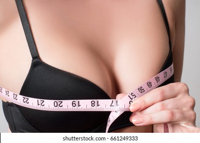 Beauty concept. Closeup of young woman measures her breast with a measuring tape