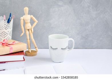 Beauty concept: eyelash extension decor on a white Cup on the table with other stylish things and tools on a gray background. - Powered by Shutterstock