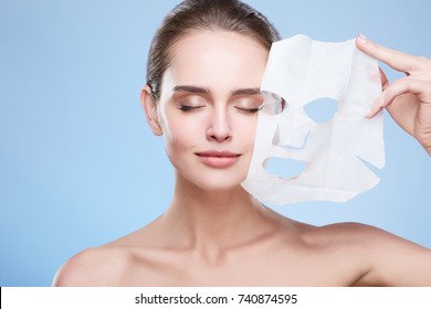 Beauty concept, head and shoulders of girl removing mask from face, face pack. Young woman with pure skin, closed eyes and smiling. Studio, grey background - Powered by Shutterstock