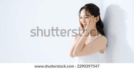 beauty concept image of an attractive asian woman with ultra violet protection and sunscreen,
wearing white sleeveless dress,
in white room with sunlight.