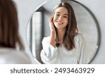 Beauty Concept. Portrait Of Attractive Happy Woman Looking At Mirror In Bathroom, Beautiful Millennial Lady Wearing White Silk Robe Smiling To Reflection, Enjoying Her Appearance, Selective Focus