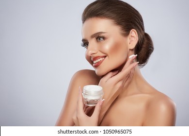 Beauty Concept, Beauty Woman Face. Closeup Of Beautiful Young Female Model With Fresh Skin Holding Cream Bottle In Hand. Portrait Of Sexy Girl Applying Cosmetic Product. Skincare Concept.