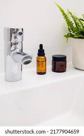 Beauty Cosmetic Product Bottle In Brown Glass And Green Potted Plant On A White Sink In Bathroom With Copy Space. Eco Friendly Sustainable Skin Care. Minimal Home Interior. Morning Beauty Routine.