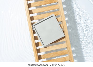 Beauty cosmetic product presentation flat lay scene made with empty square podium on a bath tray above the fresh water. Stockfoto