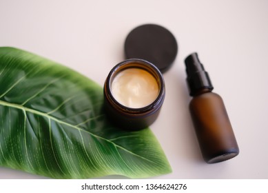 Beauty cosmetic skincare packaging.Products in amber glass jar  ,leaves on white table top view, flat lay.minimal modern