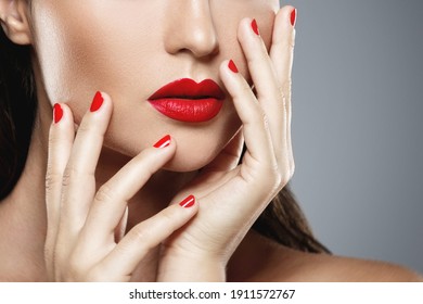 Beauty and cosmetics. Close-up of female mouth and nails with red manicure and lipstick.
