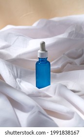 Beauty, Cosmetics And Object Concept - Bottle Of Serum On White Sheet With Folds