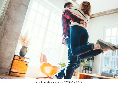 Beauty couple at home. Spending happy time together and dancing in the big spacious room, laughting and hugging. Bright loft apartment