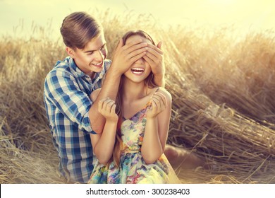 Beauty Couple Relaxing On Wheat Field Together. Teenage Girlfriend And Boyfriend Having Fun Outdoors, Kissing And Hugging, First Love Concept. Teenagers Boy And Girl In Love Together