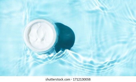 Beauty cream jar and  
bright ligh blue water. Moisturizing beauty cream, skincare and spa cosmetics. Top  view and copy space 