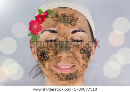Beauty day. Close-up of a woman`s face. The woman has a clay face mask and eyebrows painted black.The woman stares into the lens.Woman`s face with a clay brown mask and eyebrows painted black.