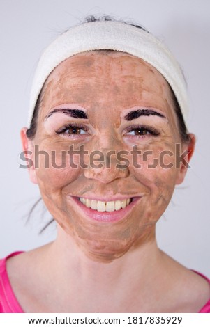 Beauty day. Close-up of a woman`s face. The woman has a clay face mask and eyebrows painted black.