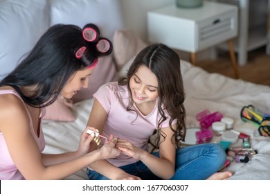 Beauty Day. Mom And Daughter Sitting On The Bed And Polishing Nails