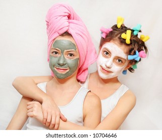 Beauty day of twin sisters, one with a towel on her head, other with hair rollers, both wearing face masks. Please check for more. - Powered by Shutterstock