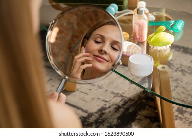 Beauty Day. Woman Wearing Towel Doing Her Daily Skincare Routine At Home. Putting On Moisturizing And Creme, Looking On Her Reflection In Mirror. Concept Of Beauty, Self-care, Cosmetics, Youth.