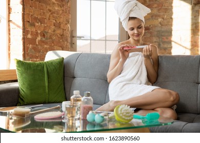 Beauty Day. Woman wearing towel doing her daily skincare and manicure routine at home. Sitting on sofa looks happy and calm. Concept of beauty, self-care, cosmetics, youth, home weekend, spa. - Powered by Shutterstock