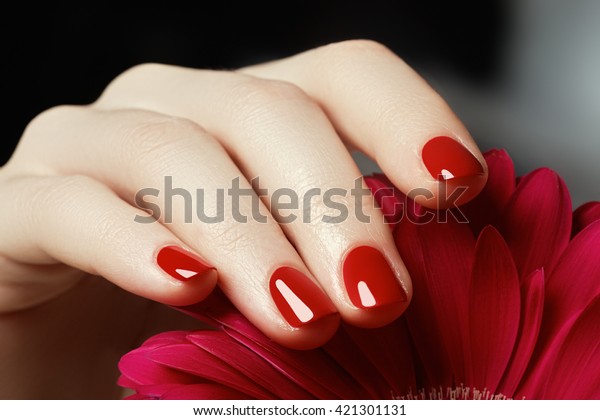 Beauty delicate hands with manicure holding\
pink flower  close up. Beautiful nails and flower close-up, great\
idea for the advertising of\
cosmetics.