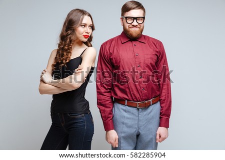 Beauty Displeased woman with smiling male nerd in funny clothes and eyeglasses