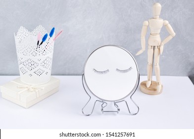 Beauty eyelash concept: eyelash extension decor on a mirror on the table with other stylish things and tools on a gray background. - Powered by Shutterstock