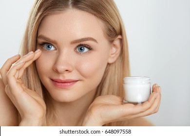 Beauty Face Care. Closeup Of Attractive Young Female Model Putting Cream On Under Eye Skin. Portrait Of Smiling Sexy Woman With Fresh Makeup Touching Facial Skin. Cosmetic Concept. High Resolution