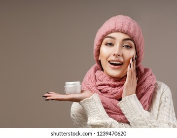 Beauty Face Care Portrait Of Attractive Young Caucasian Woman In Warm Clothing  Studio Shot Toothy Smiling Winter Applying Cream