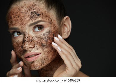 Beauty Face Care. Portrait Of Attractive Young Woman Putting Coffee Scrub On Facial Skin. Closeup Beautiful Sexy Female Model Touching Face With Hands, Exfoliating And Scrubbing Skin. High Resolution