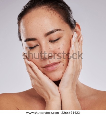 Beauty, face and skincare of woman in studio for cosmetics, dermatology and glow. Aesthetic asian model person with hands on skin for makeup, mole and facial self care for wellness on grey background